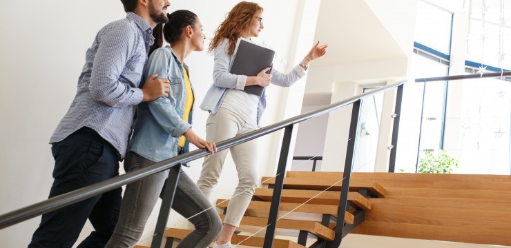 Canva Female Real Estate agent shows interior to young couple.